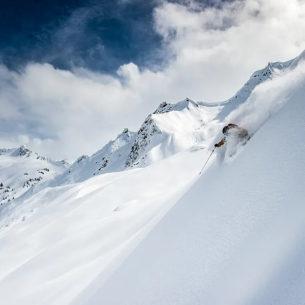 A heli-skier riding down a ski slope near Mica Heliskiing Lodge.