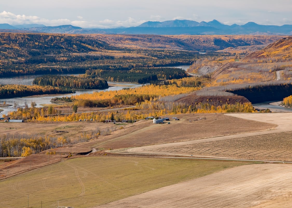 A monochromatic, hilly landscape surrounds a winding river.