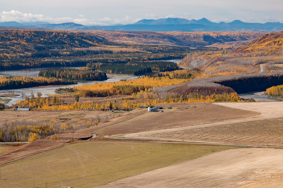 A monochromatic, hilly landscape surrounds a winding river.