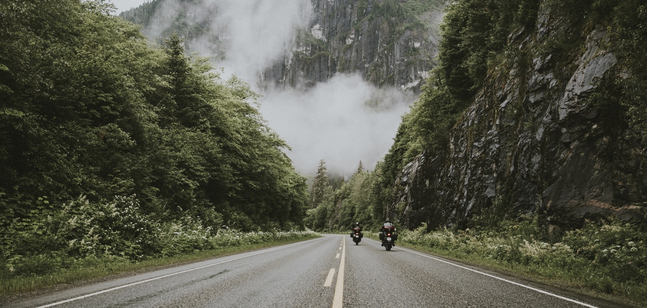 Two people on motorcycles driving down the road