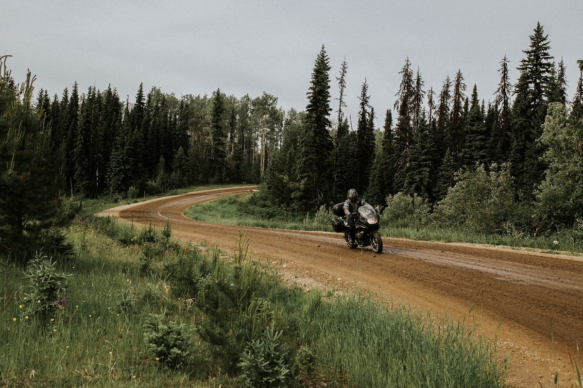 A person driving down a dirt road on a motorcycle
