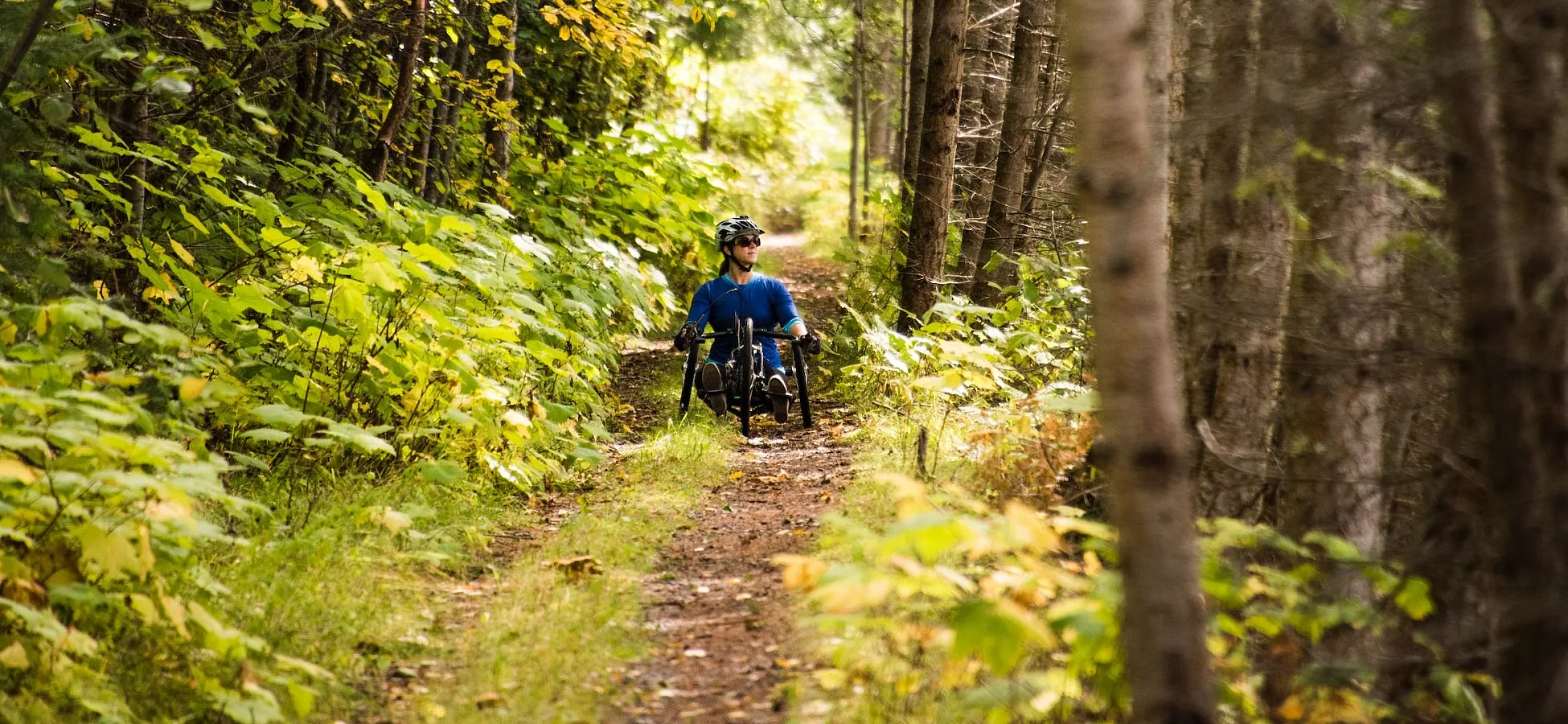 Un ciclista adaptado en el sendero accesible Galena Trail en New Denver, BC.