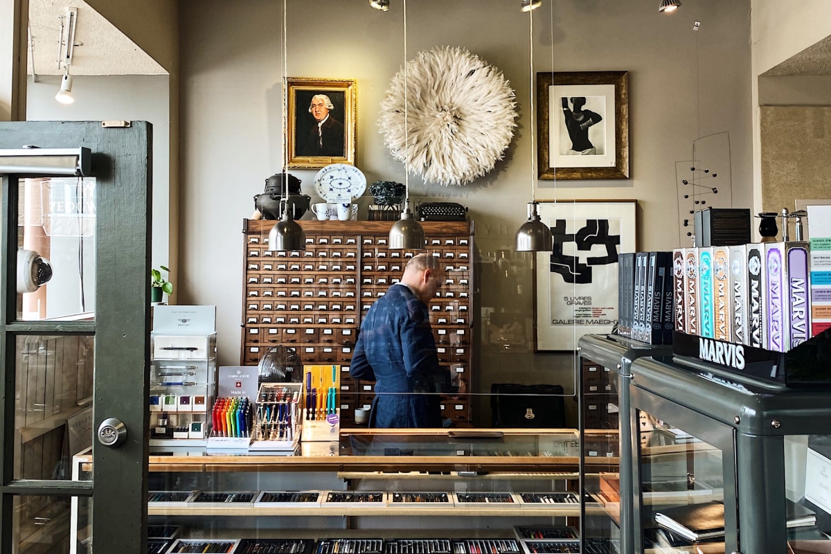 An inside view of Nikaido Gifts and Tea in Steveston. A collection of books can be found upon entering, with a person behind the glass counter organizing items.