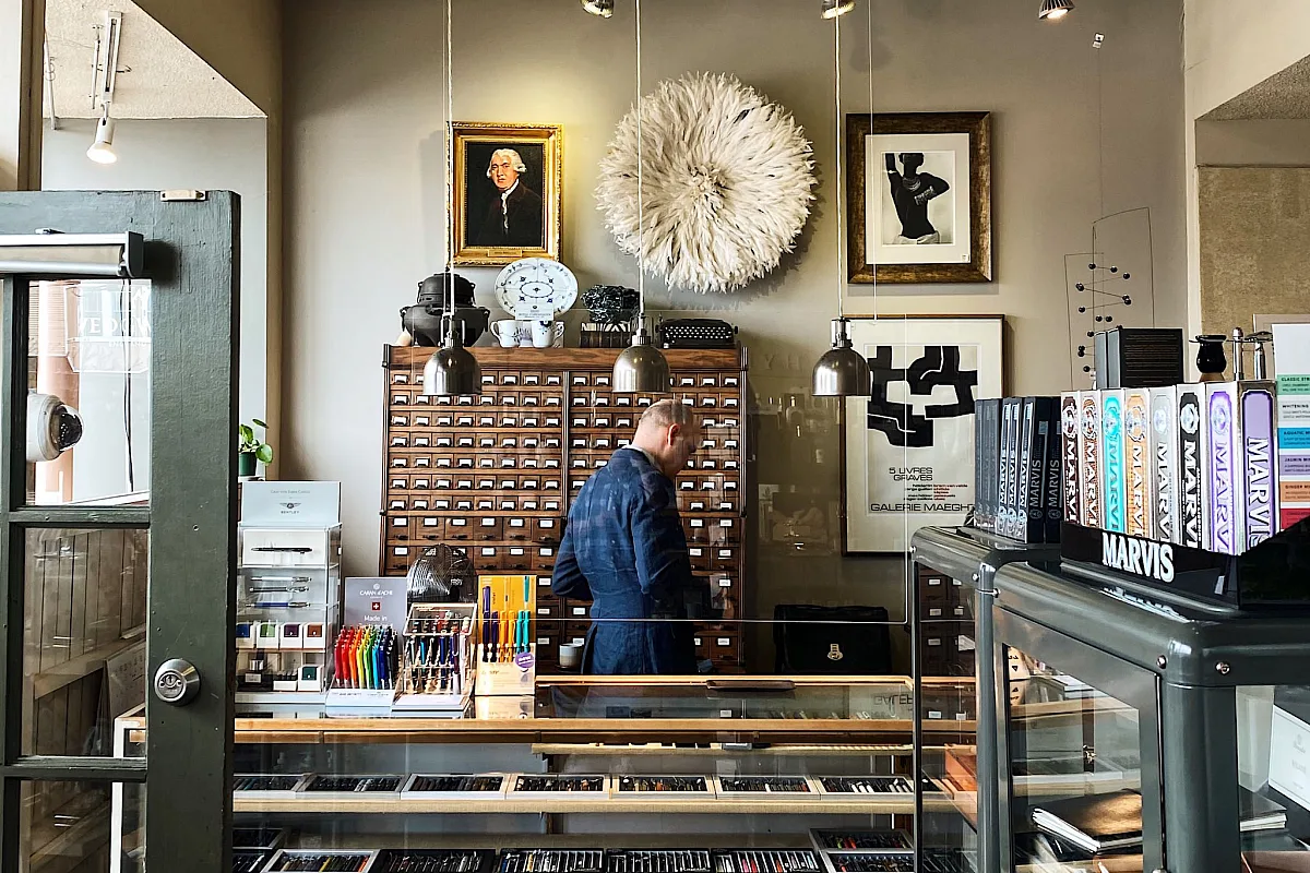 An inside view of Nikaido Gifts and Tea in Steveston. A collection of books can be found upon entering, with a person behind the glass counter organizing items.