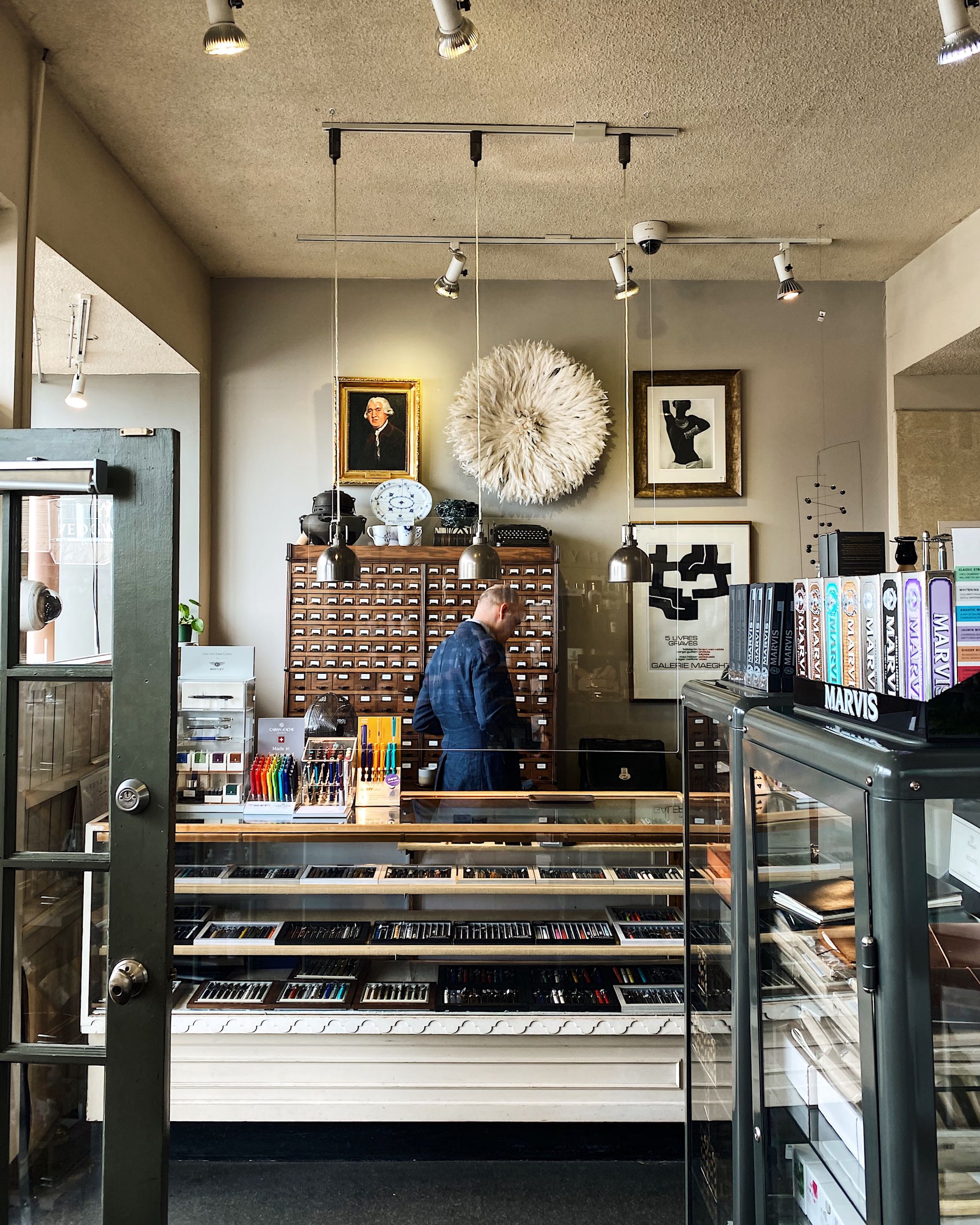 An inside view of Nikaido Gifts and Tea in Steveston. A collection of books can be found upon entering, with a person behind the glass counter organizing items.
