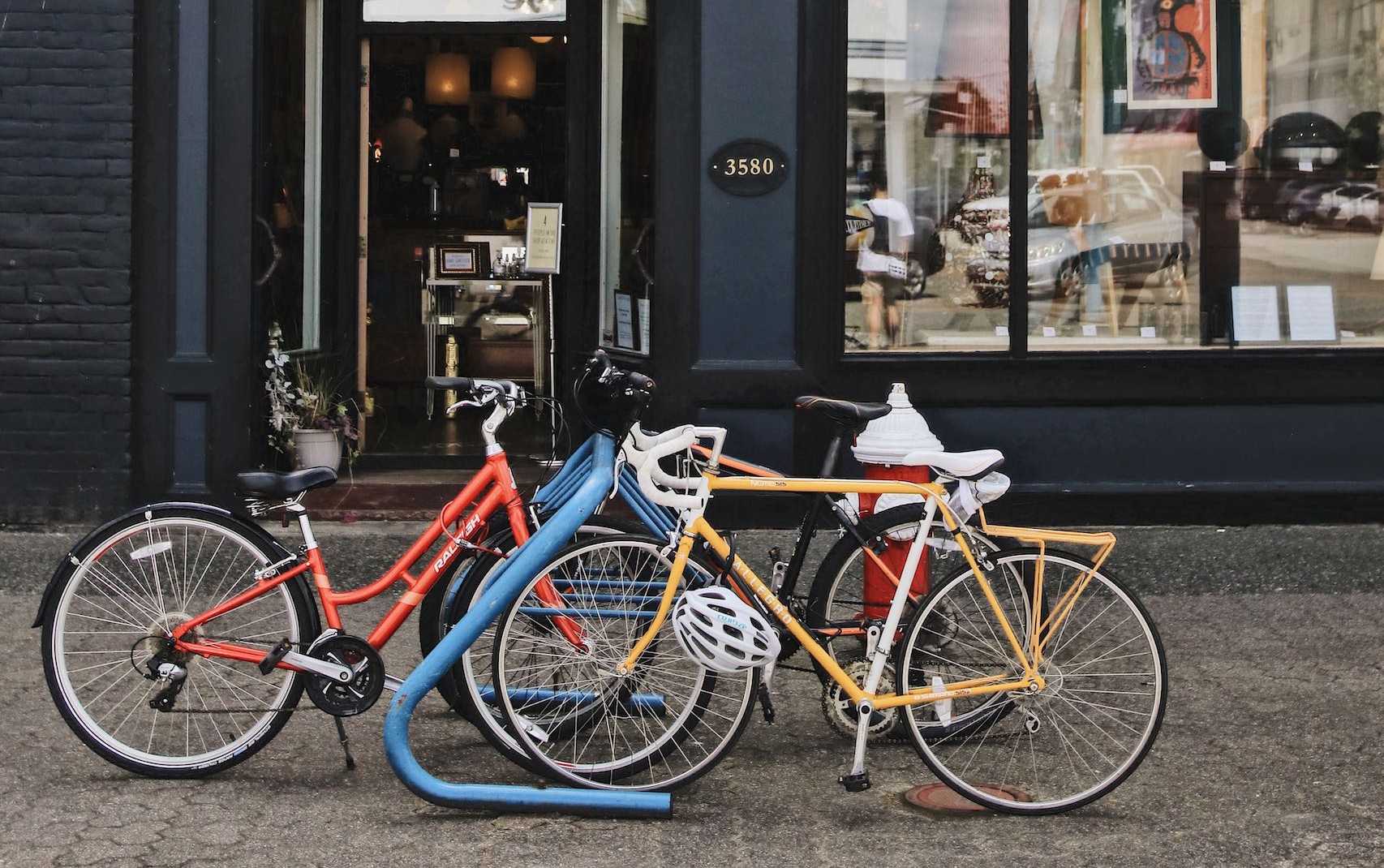 An orange and yellow bike pare parked at a pastel blue bike lock station.