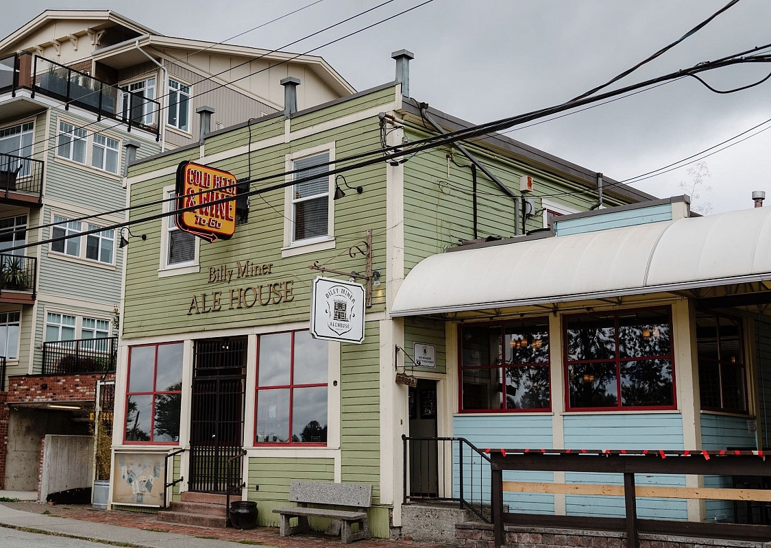 A light green paneled 2 story wood building and red windowsills is featured.