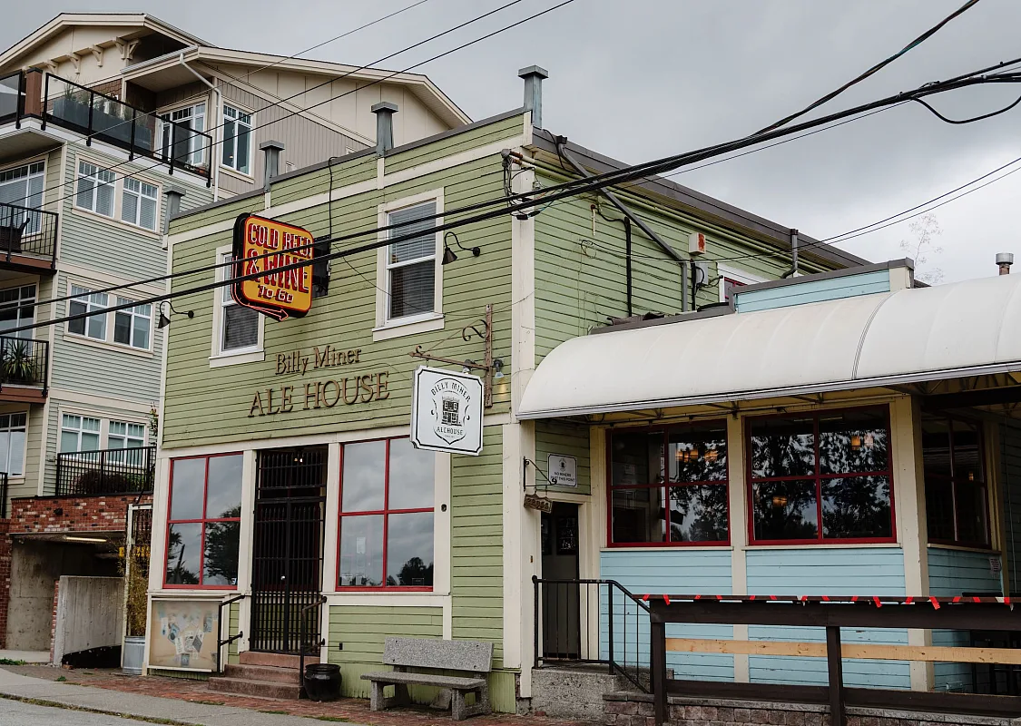 A light green paneled 2 story wood building and red windowsills is featured.