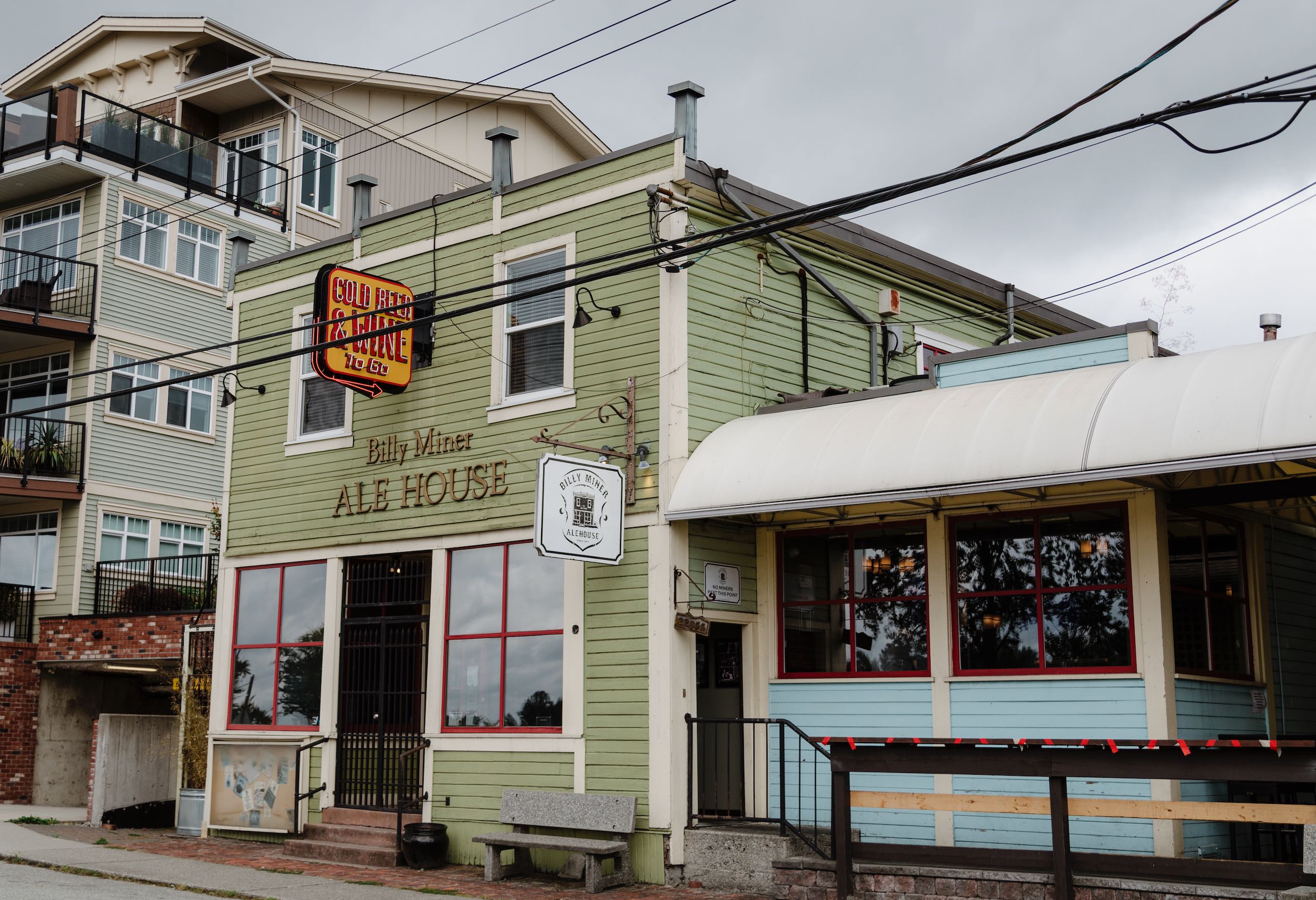 A light green paneled 2 story wood building and red windowsills is featured.