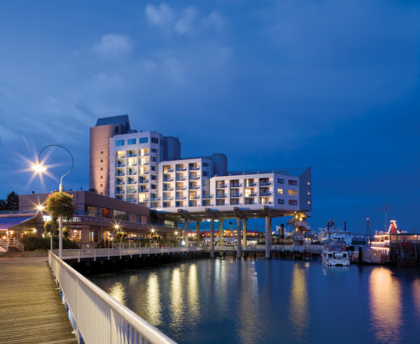 A nighttime view of the Inn At The Quay in New Westminster, lit by the boardwalk lights.