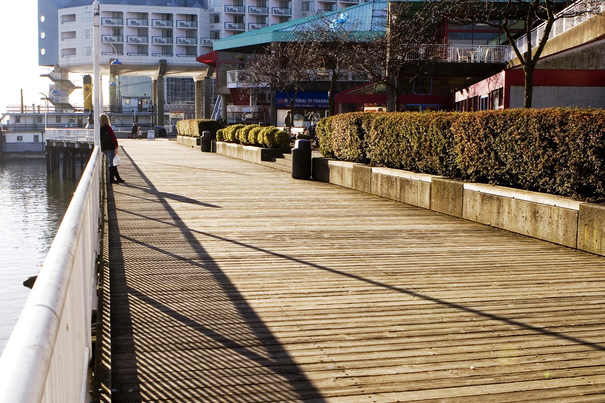 The Quay Boardwalk in New Westminster leading up to the Inn at the Quay Hotel, with low shrubs lining the boardwalk.