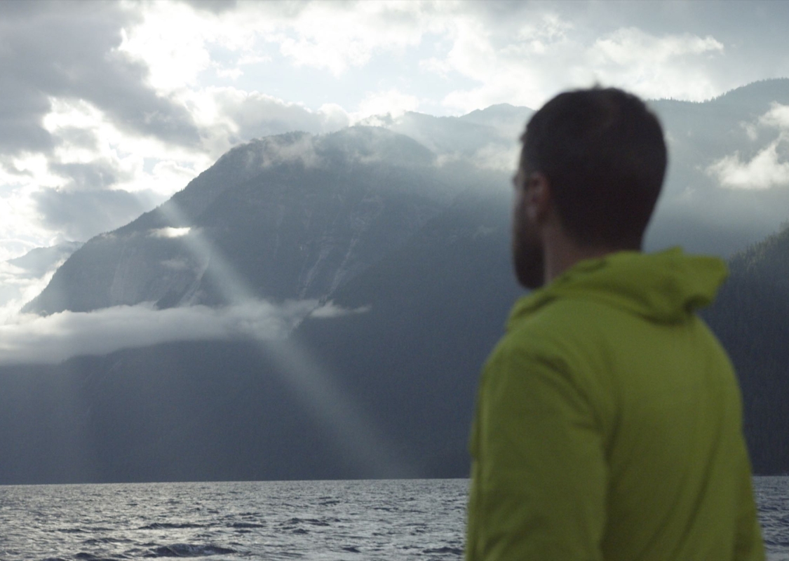 Freddy Ellmark on boat looking at mountains with sun rays Enroute to Chatterbox Falls