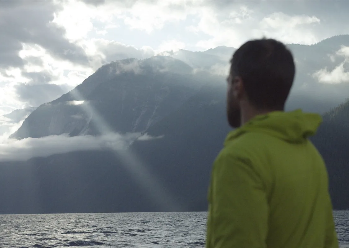 Freddy Ellmark en un bote mirando las montañas con rayos de sol En ruta a Chatterbox Falls