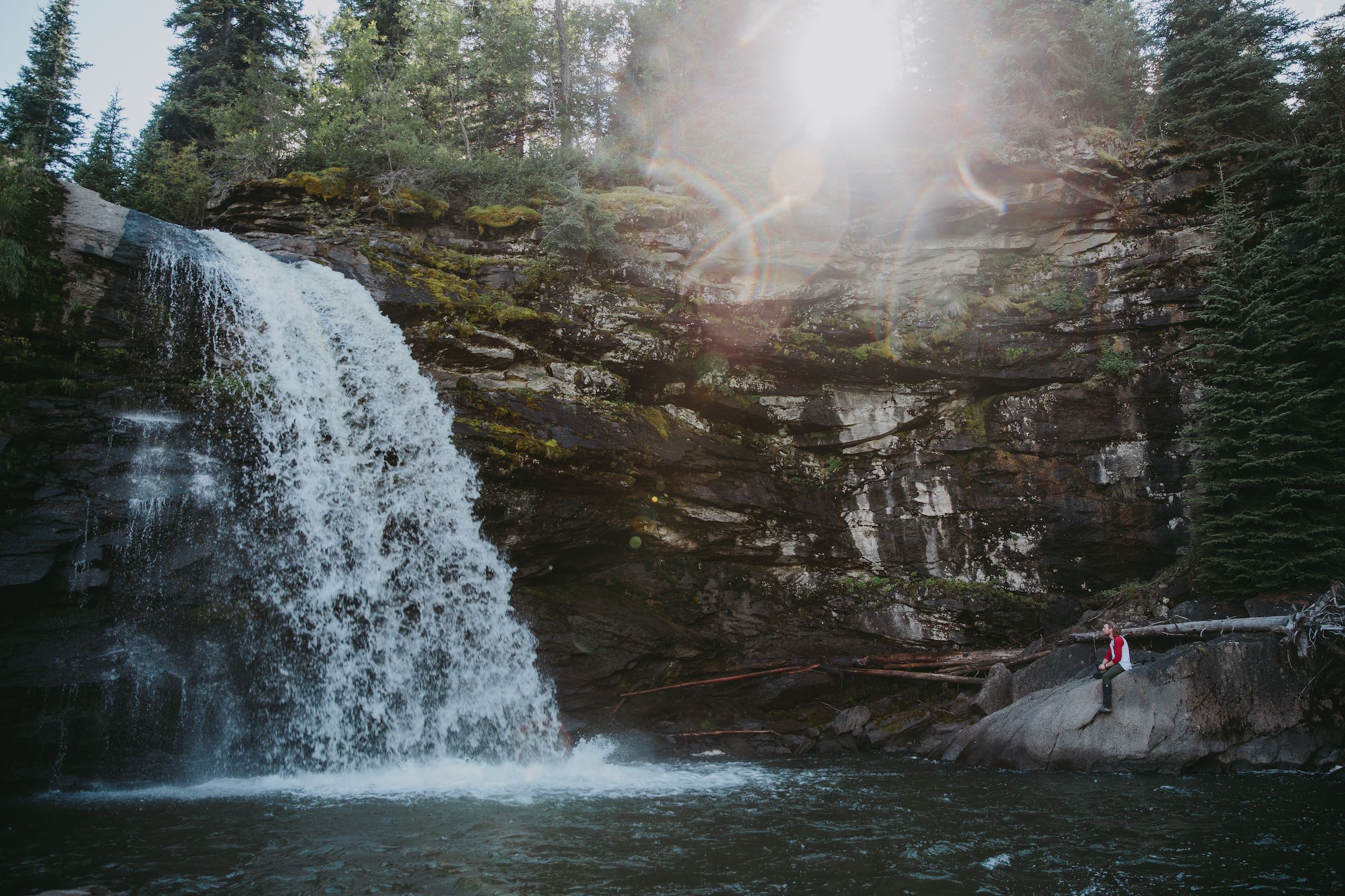 A person standing on a rock watching a waterfall