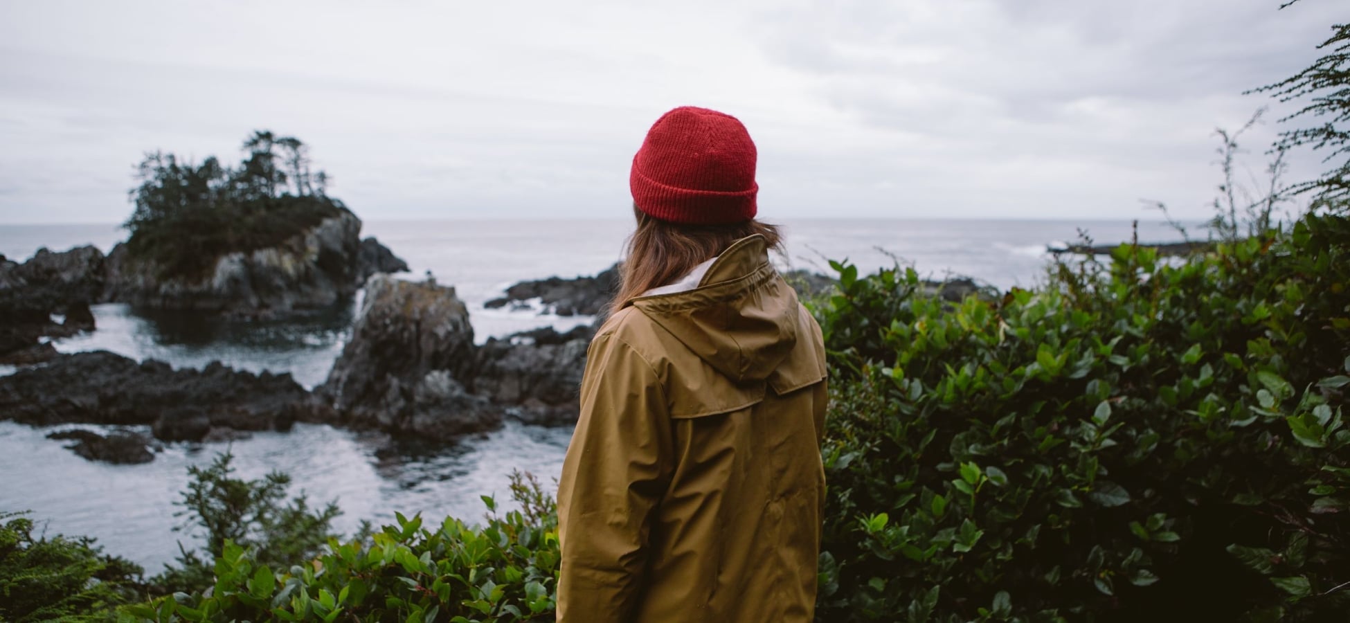 Una mujer mira la costa rocosa desde un mirador a lo largo del Wild Pacific Trail.
