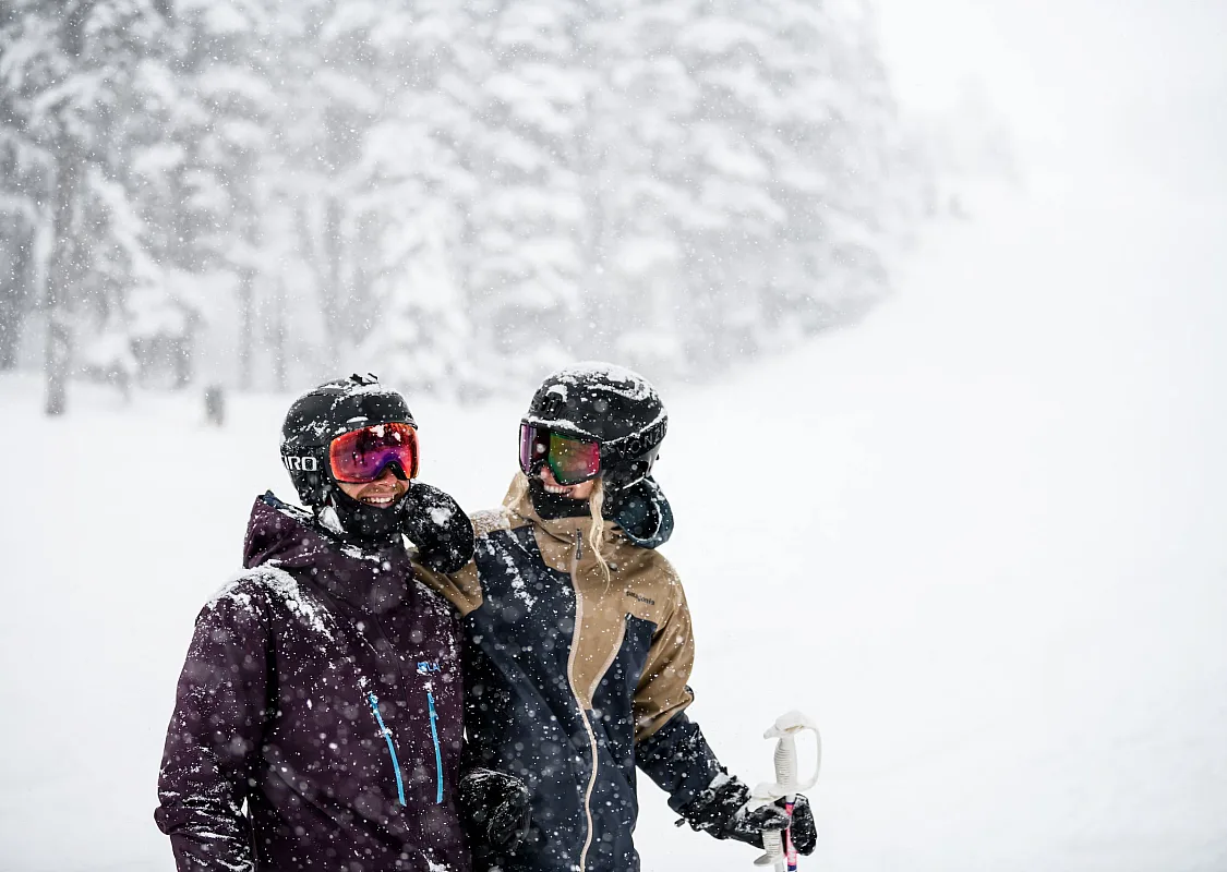 Two people enjoying the falling snow on Blackcomb Mountain in Whistler, BC.