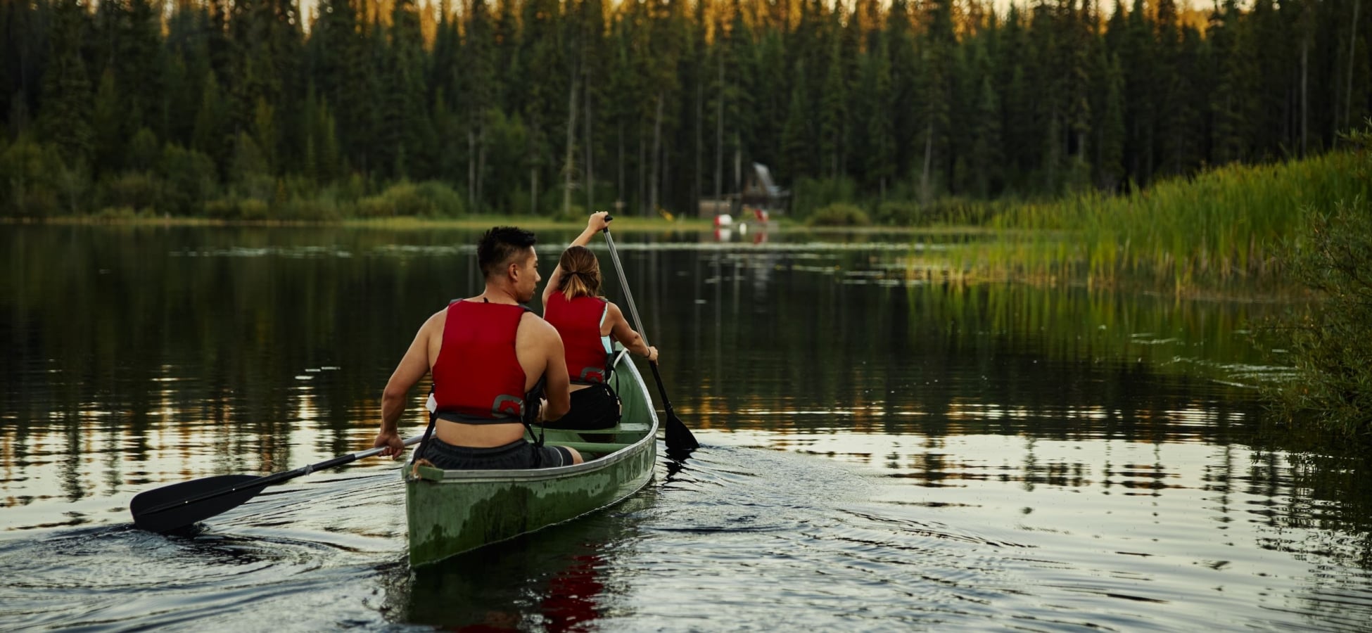 Two people canoeing at Chute Lake during sunset. Chute Lake Lodge in the background