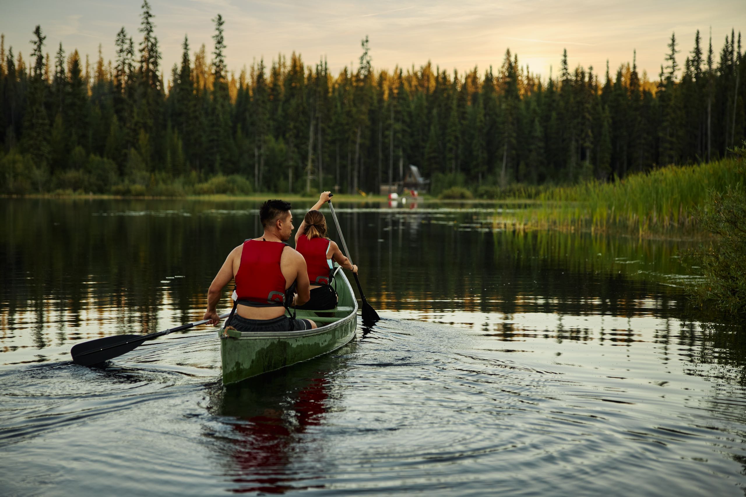 Two people canoeing at Chute Lake during sunset. Chute Lake Lodge in the background