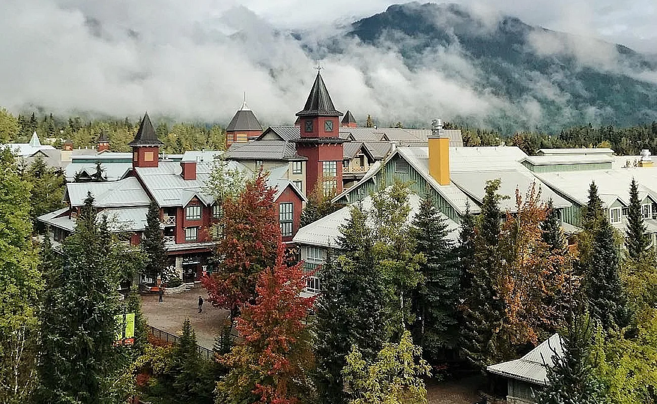 Fall colours in Whistler Village with low clouds and mountains in the background.