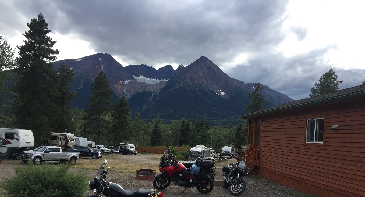Multiple vehicles parked outside a cabin by a mountain