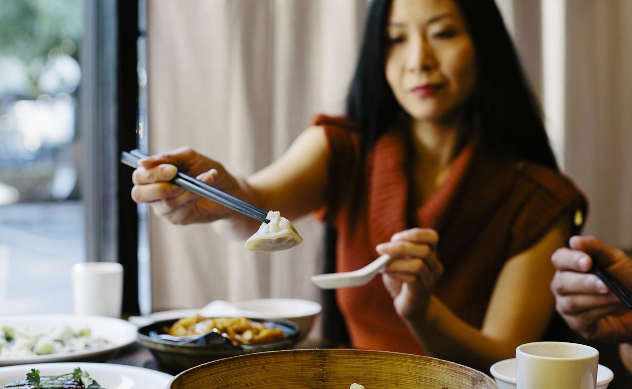 A woman is eating dumplings at a table in a restaurant.