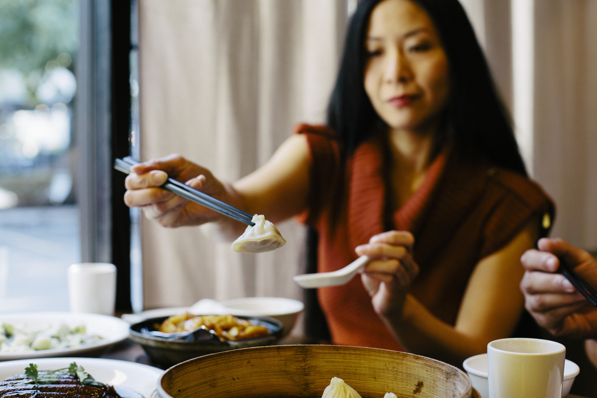 A woman is eating dumplings at a table in a restaurant.