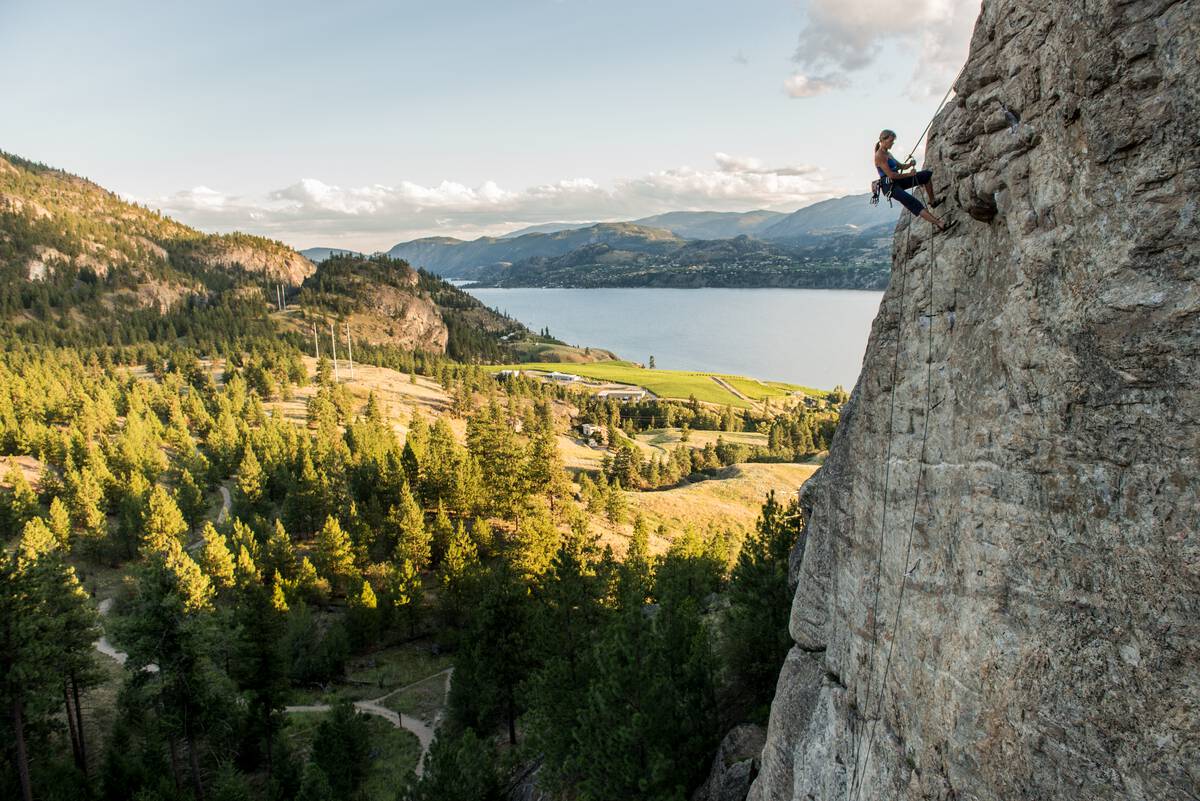 A rock climber rappels from the route Plumb Line on The Fortress with a view of Skaha Lake near Penticton | Kari Medig