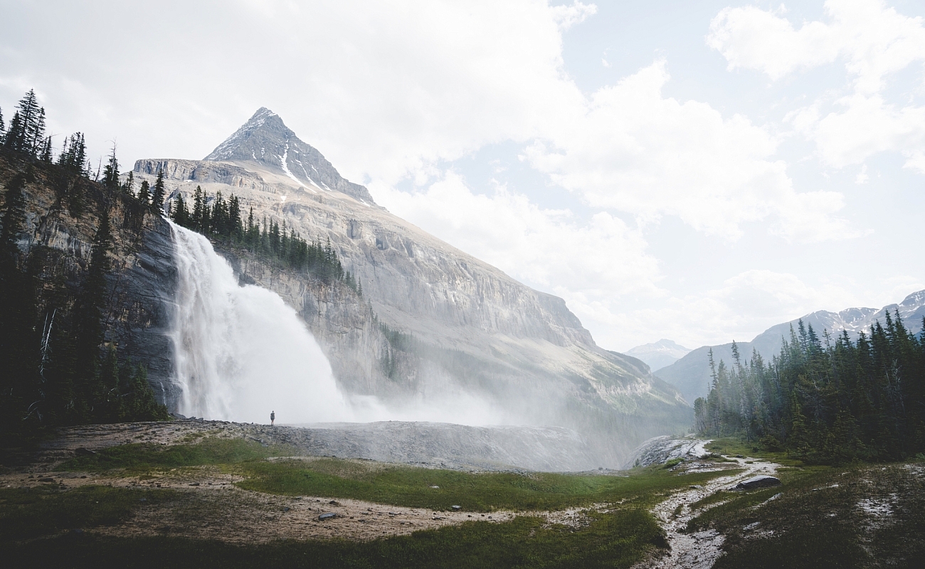 A figure is shown is hiking at Emperor Falls on the Berg Lake Trail in Mount Robson Provincial Park near Invermere, with cascading water in the background.