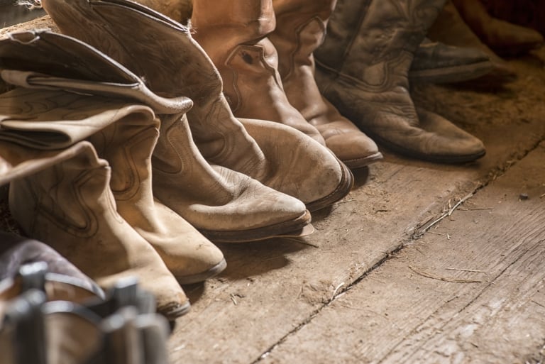 Four pairs of cowboy boots are lined up along a wooden floor at the Terra Nostra Guest Ranch.
