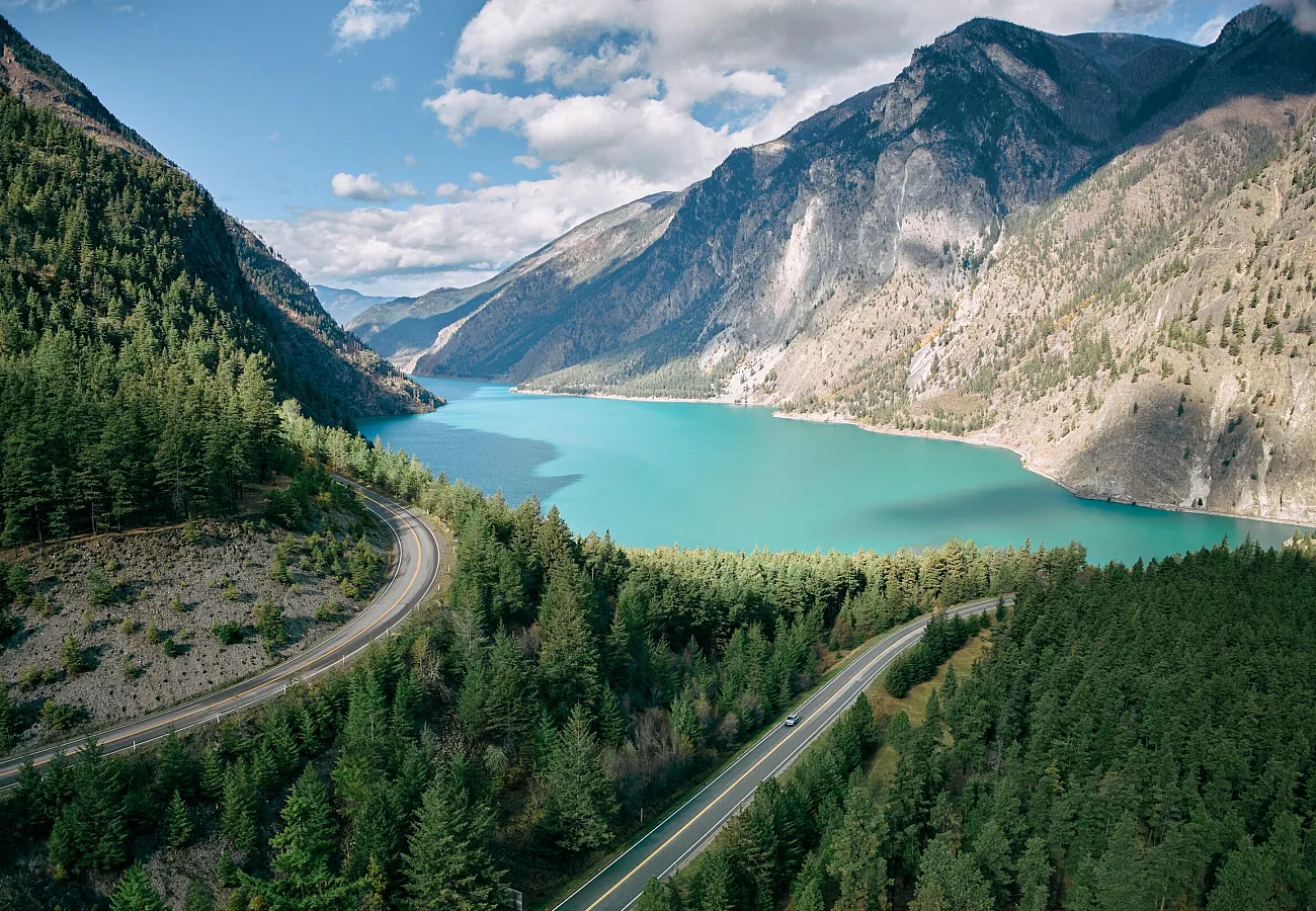 lago turquesa rodeado de bosque en primer plano y artemisa al fondo.