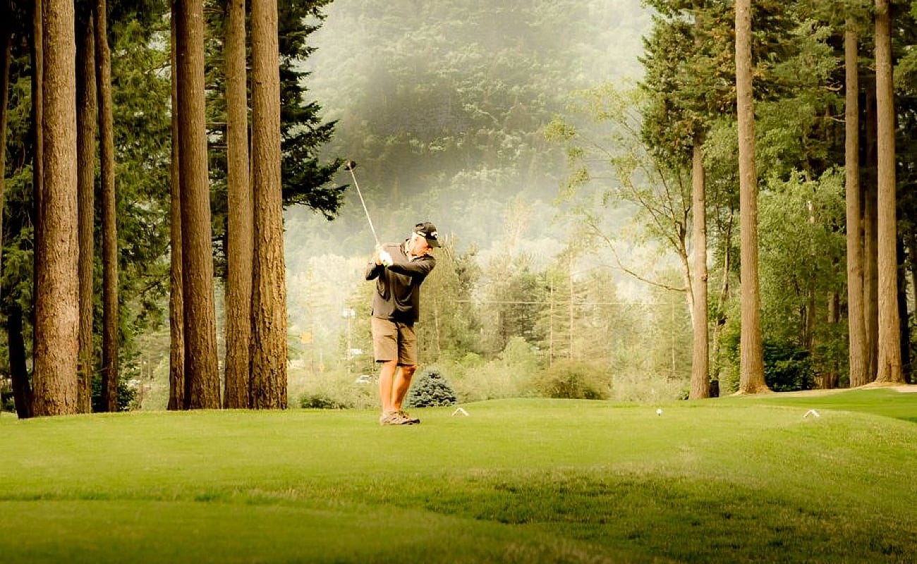 A person hits a golf ball on the fairway