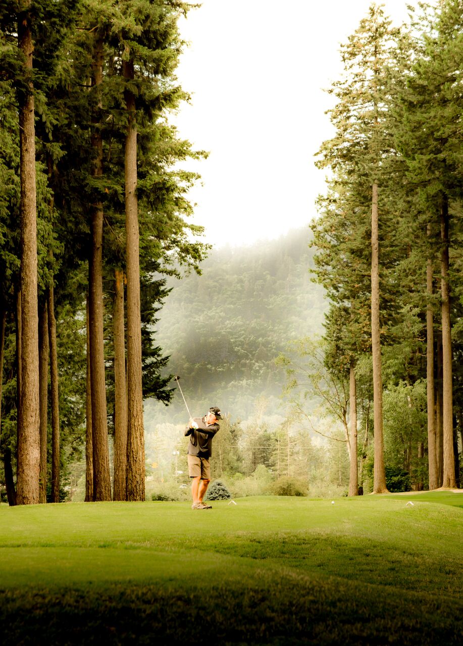 A person hits a golf ball on the fairway