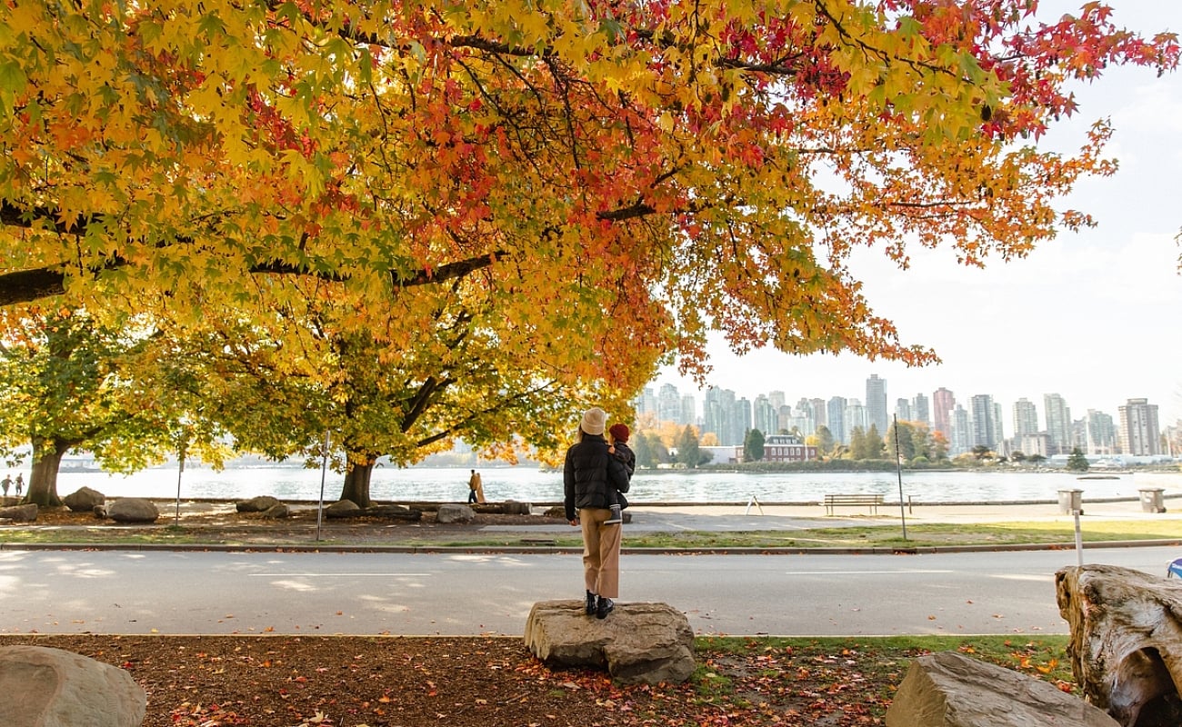 Eine Person hält ein Kind, das auf den Stanley Park in Vancouver blickt.