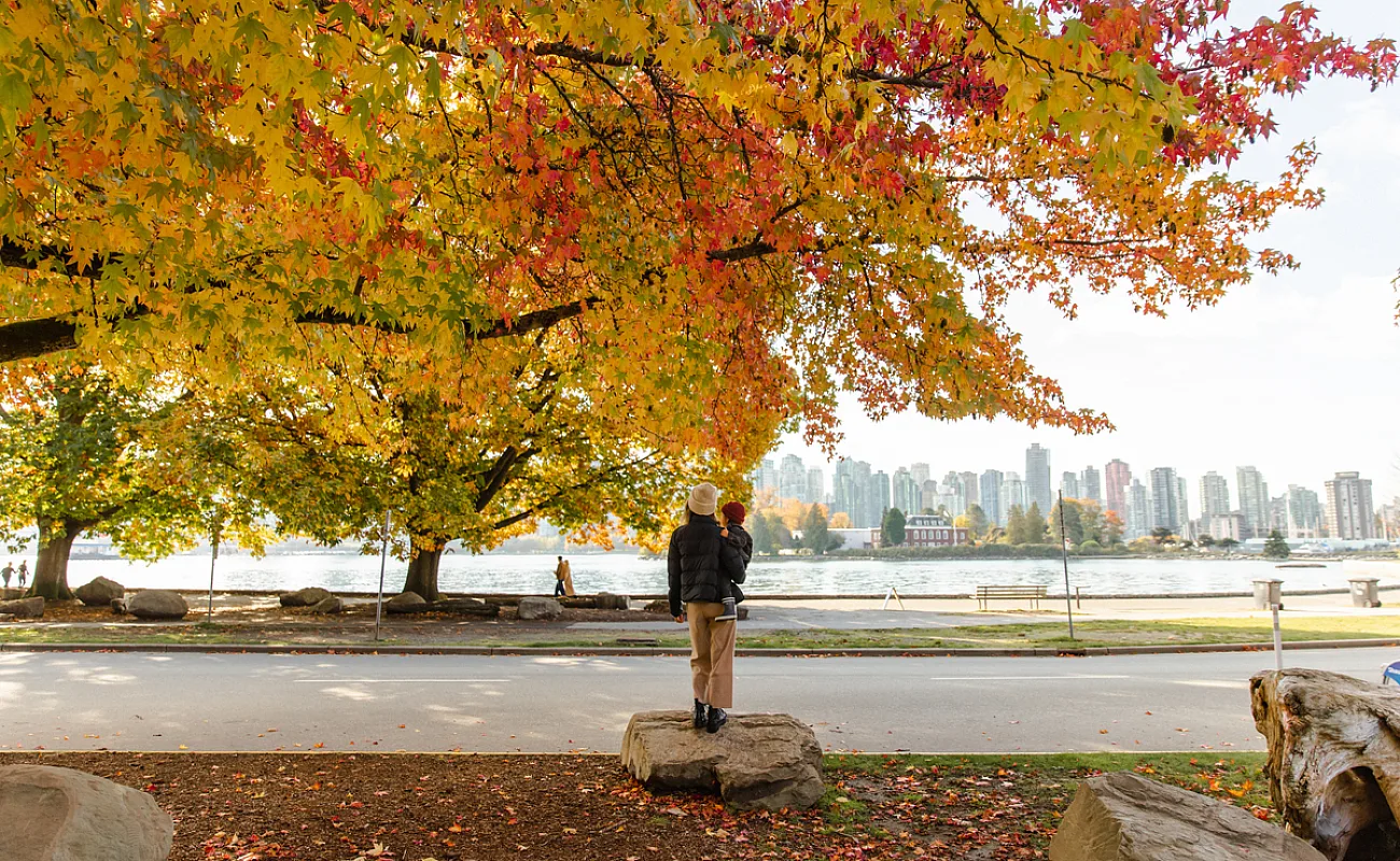 Una persona sostiene a un niño mientras miran hacia Stanley Park en Vancouver.