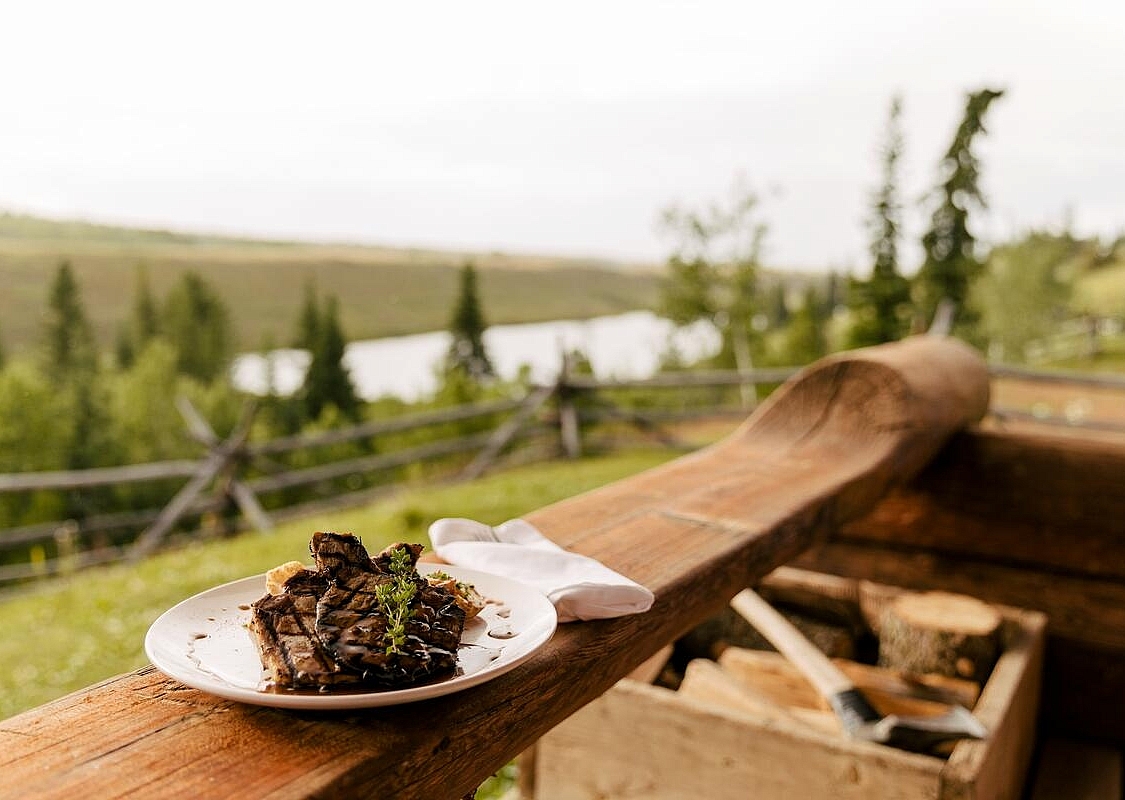 Ein Teller Essen steht auf einem Holzgeländer mit Blick auf einen See.