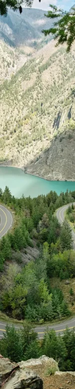 View toward a turquoise lake with a forested landscape in the foreground and sagebrush-covered mountains in the background.