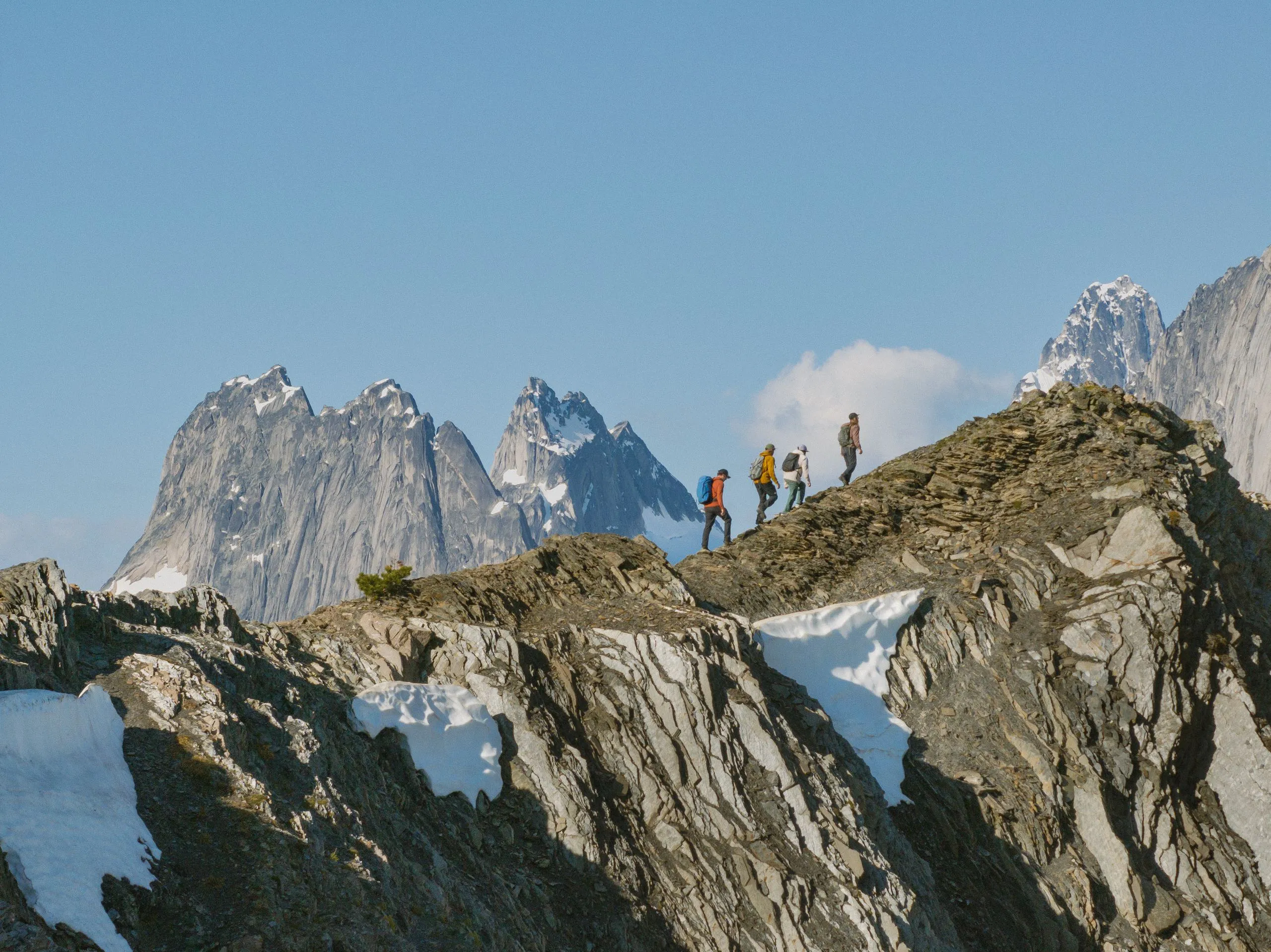 Drei Freund*innen machen Heli-Hiking inmitten der Gletscher und Bergspitzen der Bugaboos mit ihrem Guide von CMH Bugaboos.