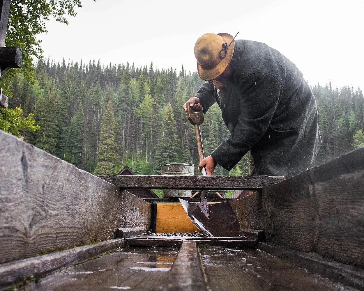 Un buscador de oro limpiando la caja de criba en la noria de Cornish, en el Parque y Pueblo Histórico de Barkerville.