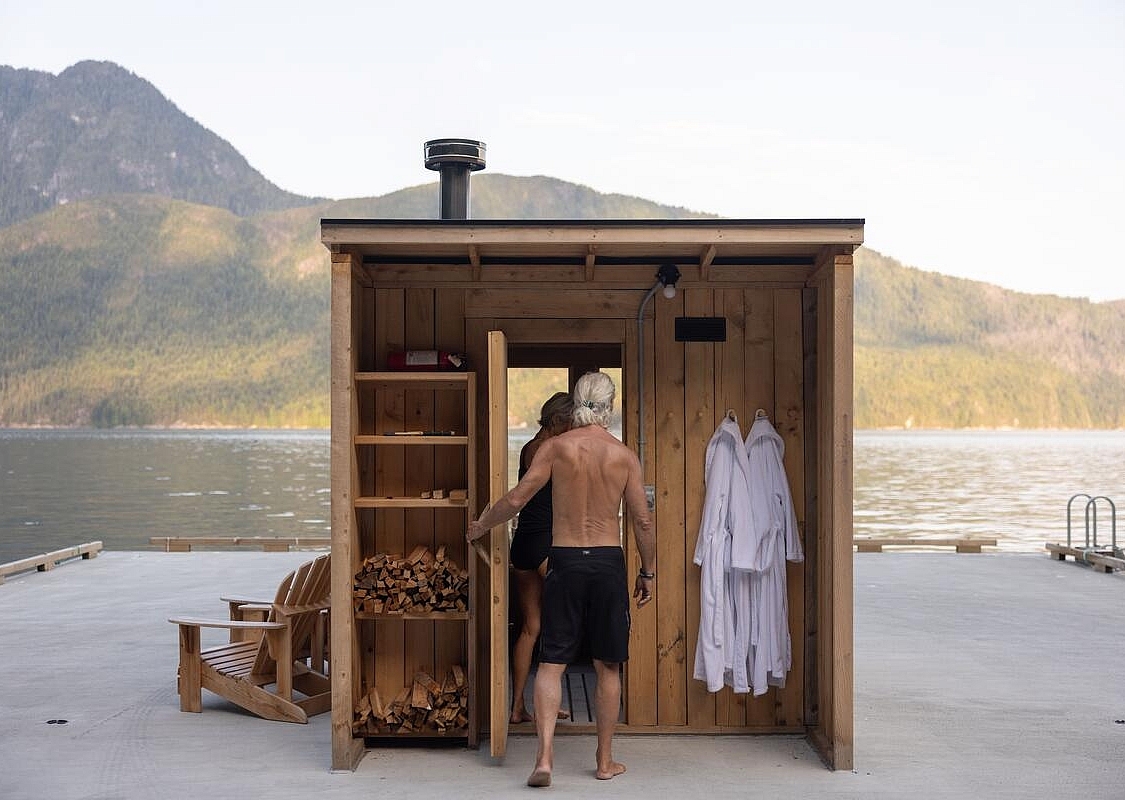 Gäste betreten die mit Holz beheizte Zedernsauna auf dem Schwimmsteg im Klahoose Wilderness Resort im Desolation Sound / Klahoose-Gebiet.