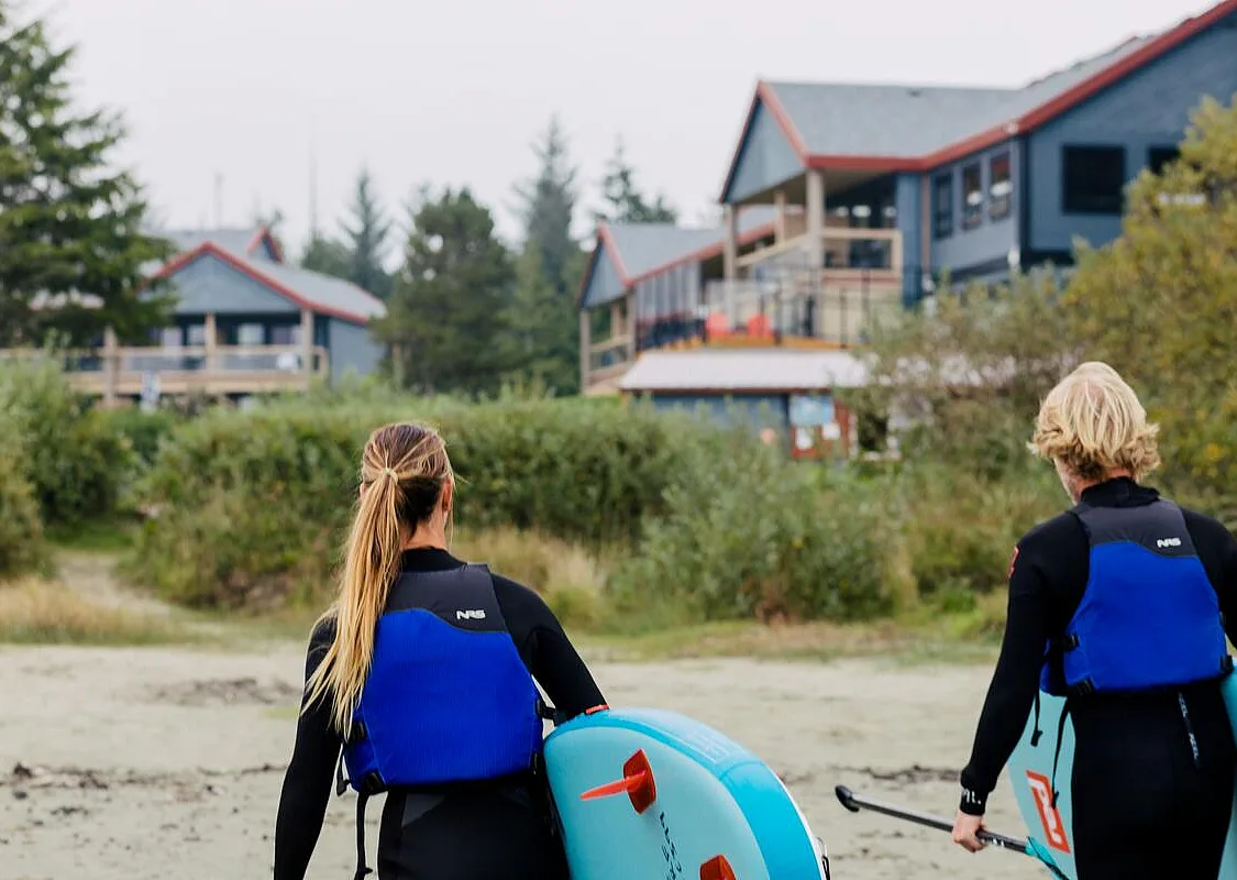 Dos personas con tablas de surf de remo en el Pacific Sands Beach Resort de Tofino.