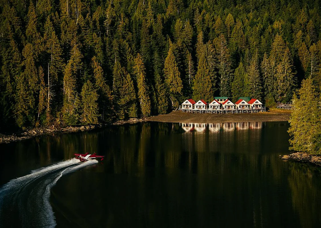 Boat travelling across the water toward the waterfront accommodations at Nimmo Bay Wilderness Resort on Vancouver Island.