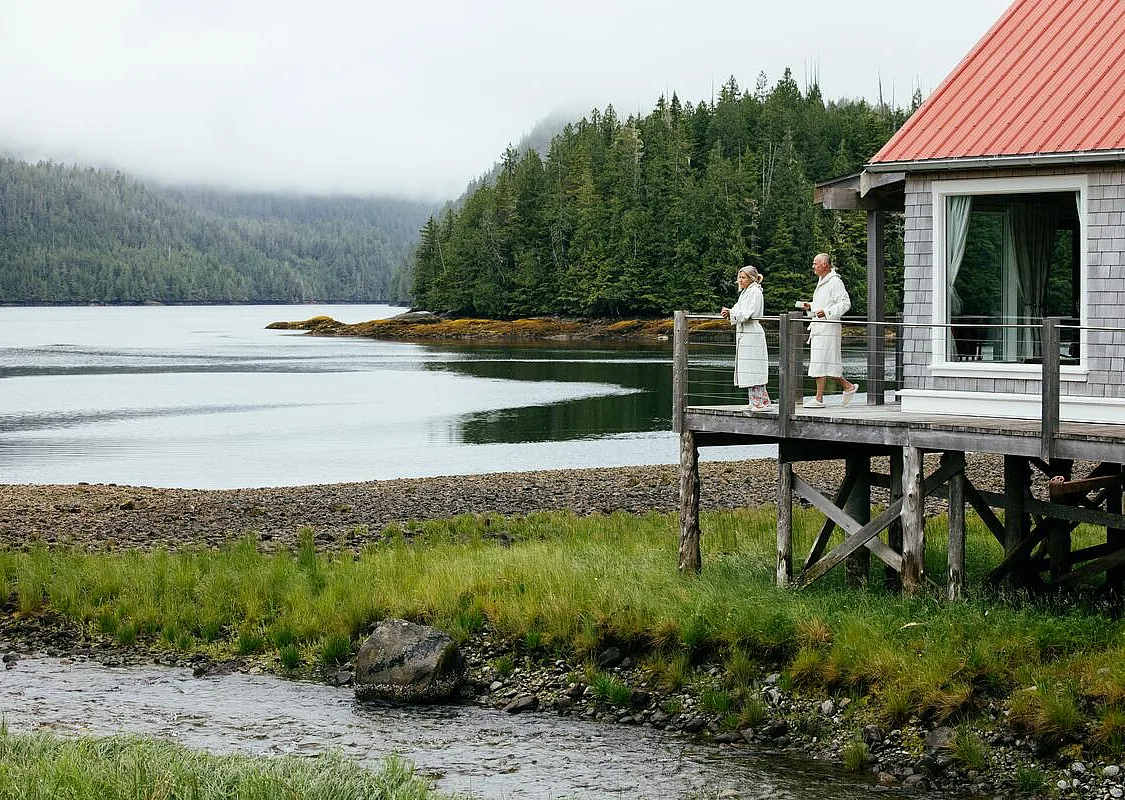 Guests in robes taking in the waterfront view from a guest cabin at Nimmo Bay Wilderness Resort on Vancouver Island.