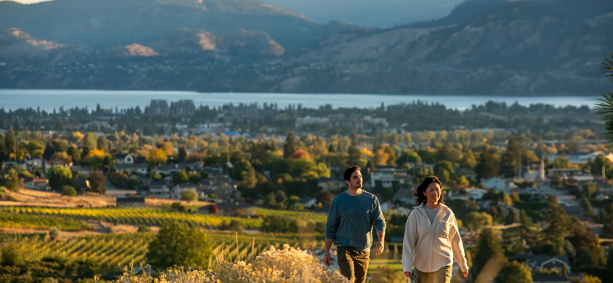 Una pareja haciendo senderismo en la montaña Munson, con Penticton y el lago Okanagan al fondo.