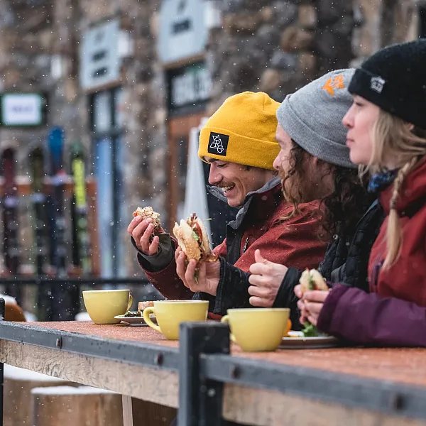 A trio of skiers enjoying lunch and coffee at Kicking Horse Mountain Resort.