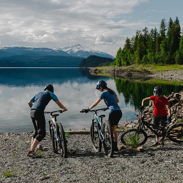 Three mountain bikers getting back on their bikes after cooling off in the lake at Mount Abriel in Nakusp.