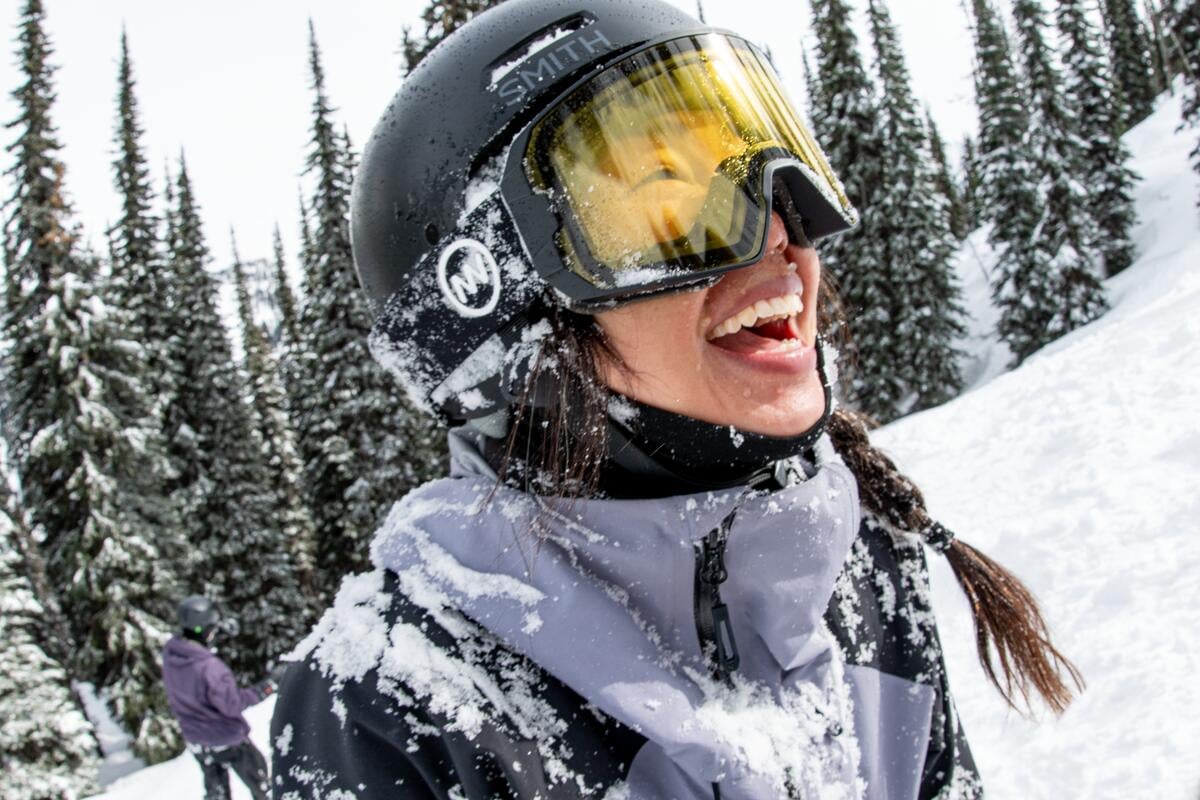 A smiling snowboarder at Whitewater Mountain Resort in Nelson, covered in fresh snow.