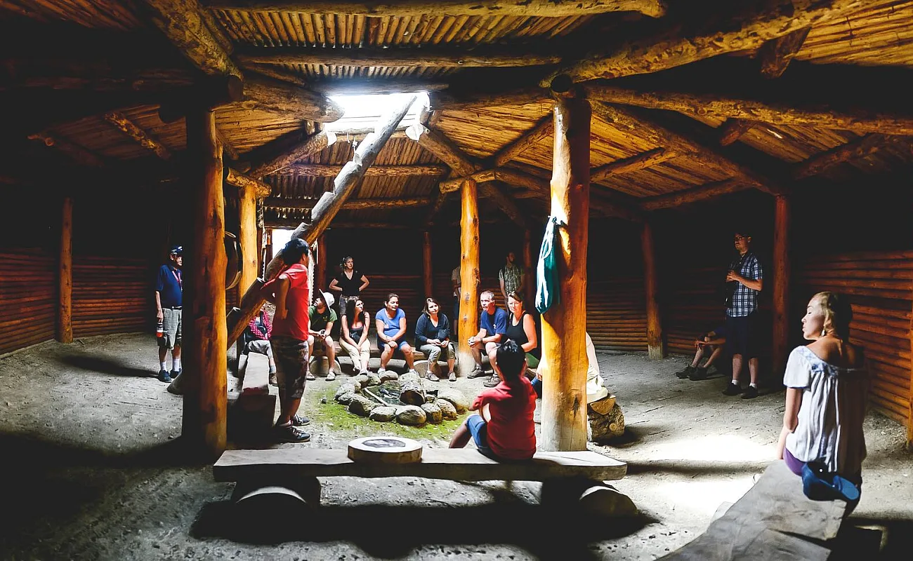 A group gathers in an Indigenous pithouse to learn about Indigenous culture through Xwisten Experience Tours