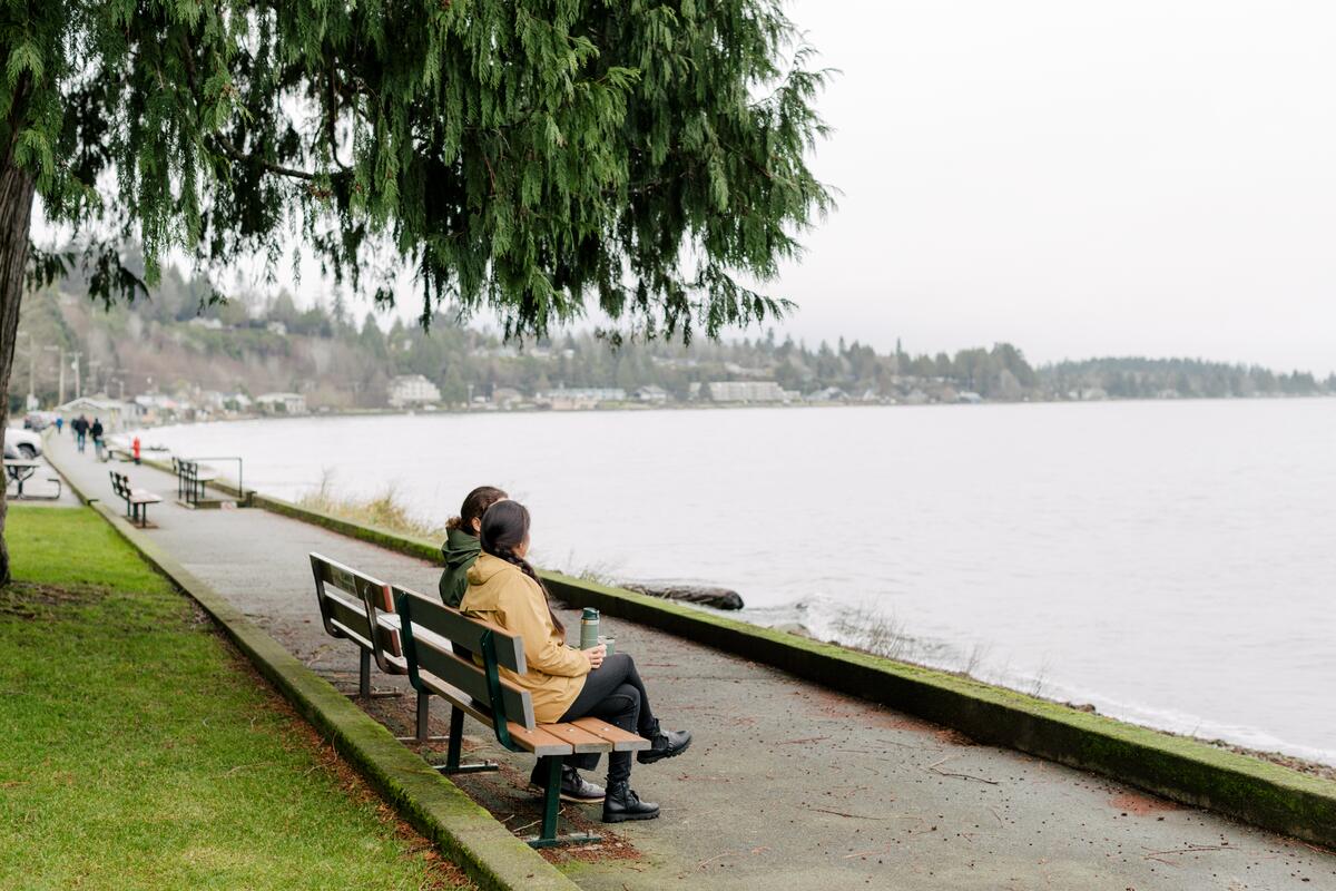 Couple sitting on a bench overlooking the ocean in Qualicum Beach.