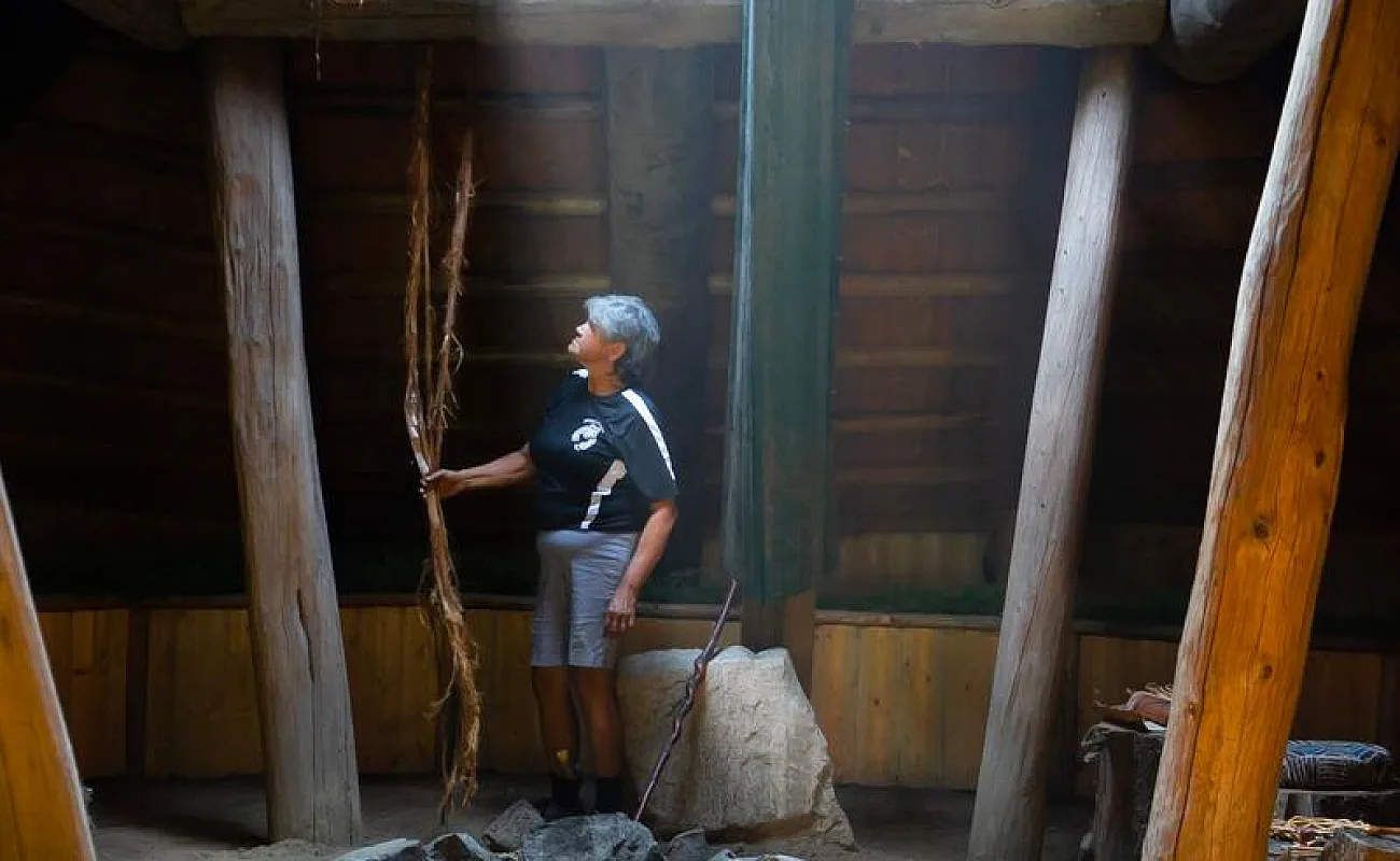 Indigenous interpreter in a historic pit house/lodge at Tuckkwiowhum Heritage Village