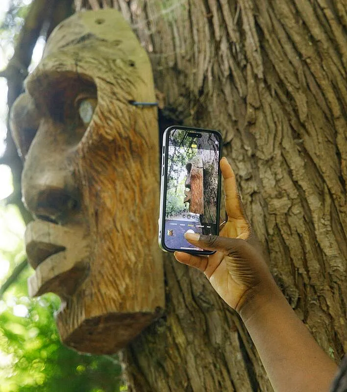 A person taking a photo of an indigenous carving on a tree at Syéxw Chó:leqw Adventure Park in Hope.
